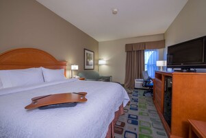 Una habitación de hotel con una cama grande, un escritorio con computadora, un televisor y una silla.