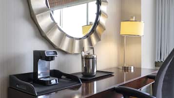 Ein Hotelzimmer mit einer Kaffeemaschine, einem Wasserkocher und einer Lampe auf einem Holztisch.