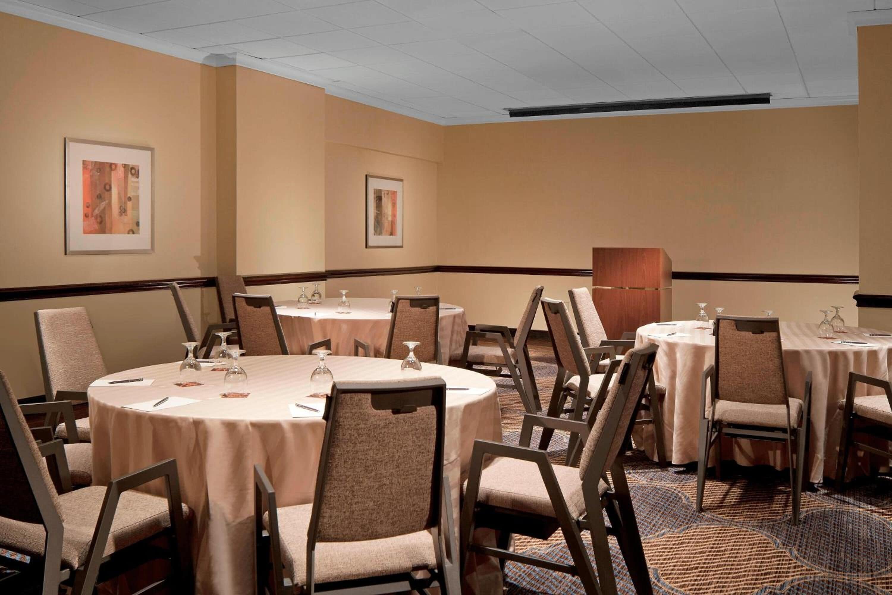 A conference room with multiple round tables, each set with chairs and glassware.