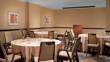 A conference room with multiple round tables, each set with chairs and glassware.