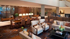 A spacious lobby with a dining area, seating arrangements, and a staircase leading to an upper level.