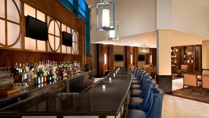 A bar area with a long counter, multiple seating options, and a modern interior design.