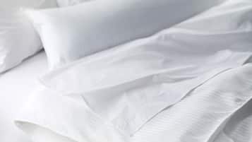 A neatly made bed with white linens and pillows.