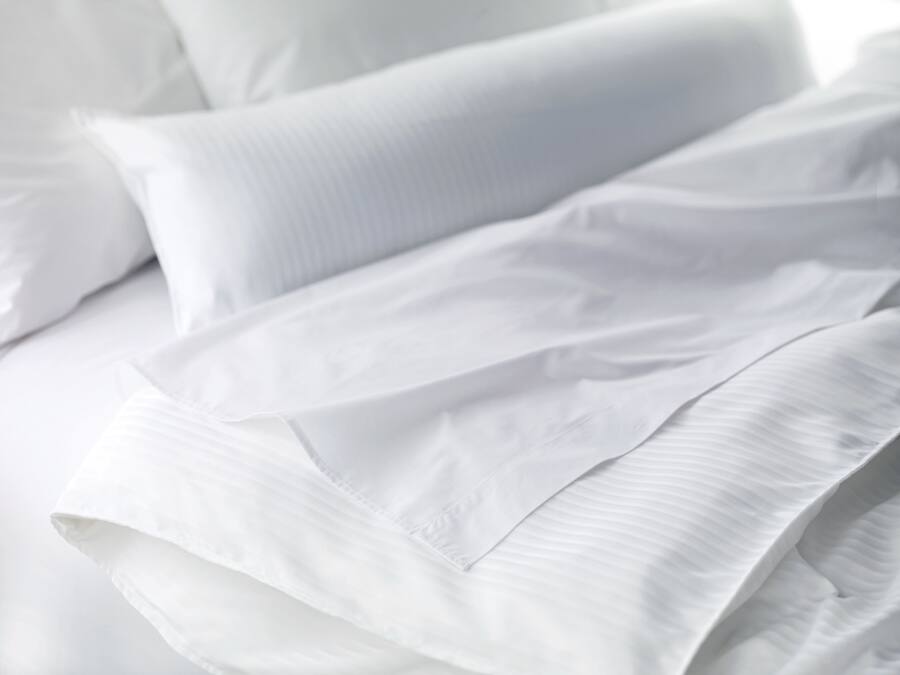 Ein ordentlich bezogenes Bett mit weißen Leinen und Kissen.