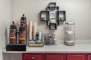 A coffee station with a coffee machine, cups, and a sign indicating hours of operation. - Red Roof Inn Queensbury (Queensbury)