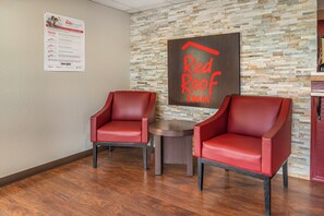 A Red Roof Inn lobby with two leather chairs, a stone wall, and a Red Roof sign. - Red Roof Inn Queensbury (Queensbury)