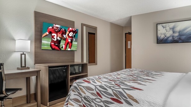 A hotel room with a bed, a desk with a computer, a TV, and a microwave. - Red Roof Inn Queensbury (Queensbury)