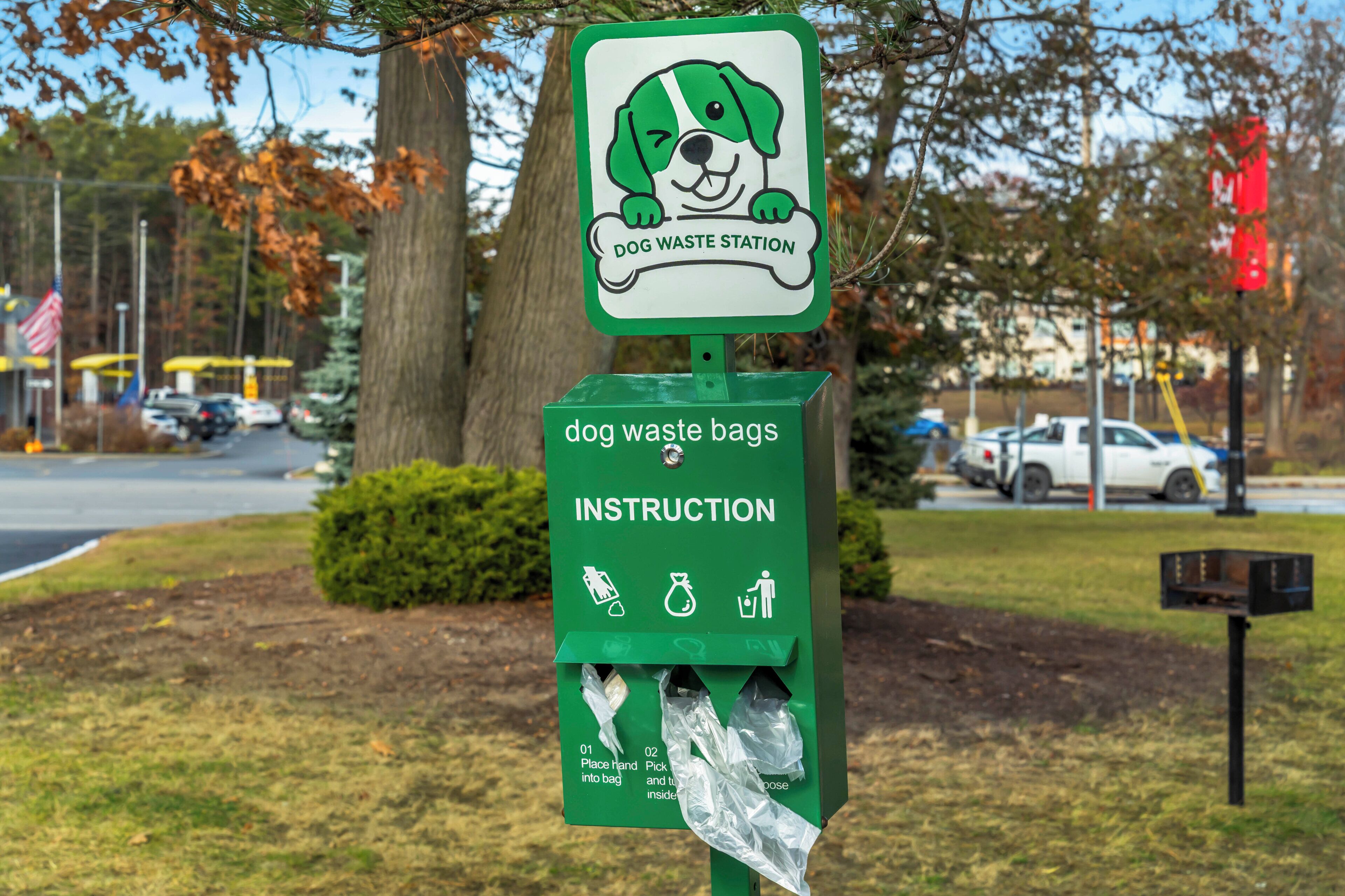 Una estación de recogida de deseches caninos con un letrero verde e ilustración de un perro caricaturesco.