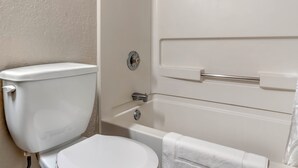 A bathroom with a toilet, a bathtub, and a towel rack. - Red Roof Inn Queensbury (Queensbury)