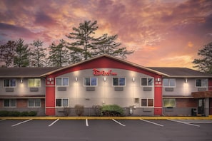 A Red Roof Inn with a red and grey facade, multiple windows, and a parking lot in front. - Red Roof Inn Queensbury (Queensbury)