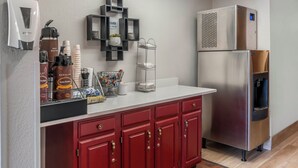 Una kitchenette equipada con cafetera, dispensador de agua caliente y refrigerador.