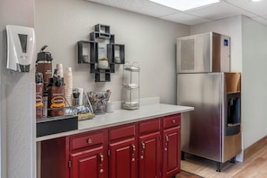A kitchenette with a coffee machine, hot water dispenser, and a refrigerator. - Red Roof Inn Queensbury (Queensbury)