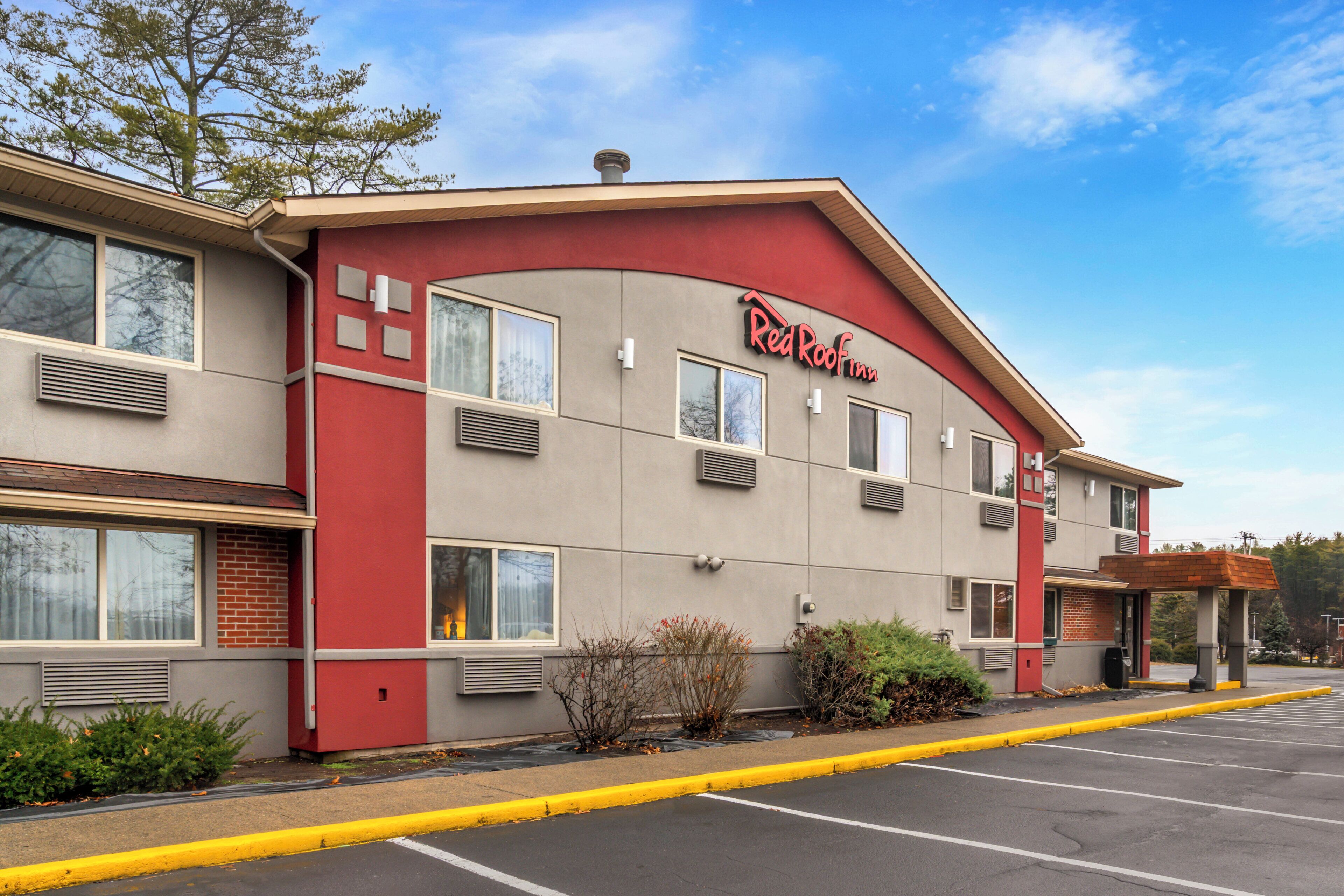 Un hôtel Red Roof Inn avec une façade rouge, de nombreuses fenêtres et un parking.