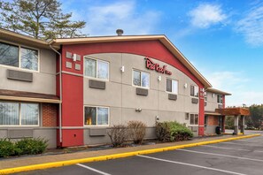 A Red Roof Inn with a red facade, multiple windows, and a parking lot. - Red Roof Inn Queensbury (Queensbury)