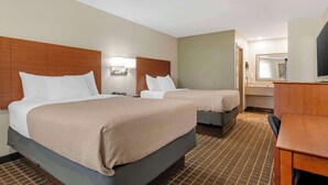 A hotel room with two beds, a desk, a mirror, and a bathroom with a sink and toilet. - Quality Inn & Suites Morrow Atlanta South (Morrow)