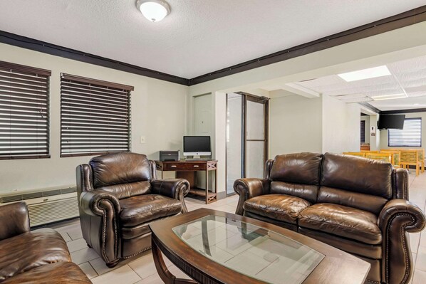 Una sala de estar con dos sofás de cuero marrón, una mesa de centro de vidrio y un televisor sobre un mueble de madera.