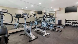 A gym with multiple exercise machines, a bench, and a wall-mounted TV. - Quality Inn & Suites Morrow Atlanta South (Morrow)