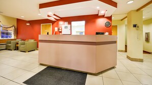 A reception area with a reception desk, seating area with chairs, and a clock on the wall.