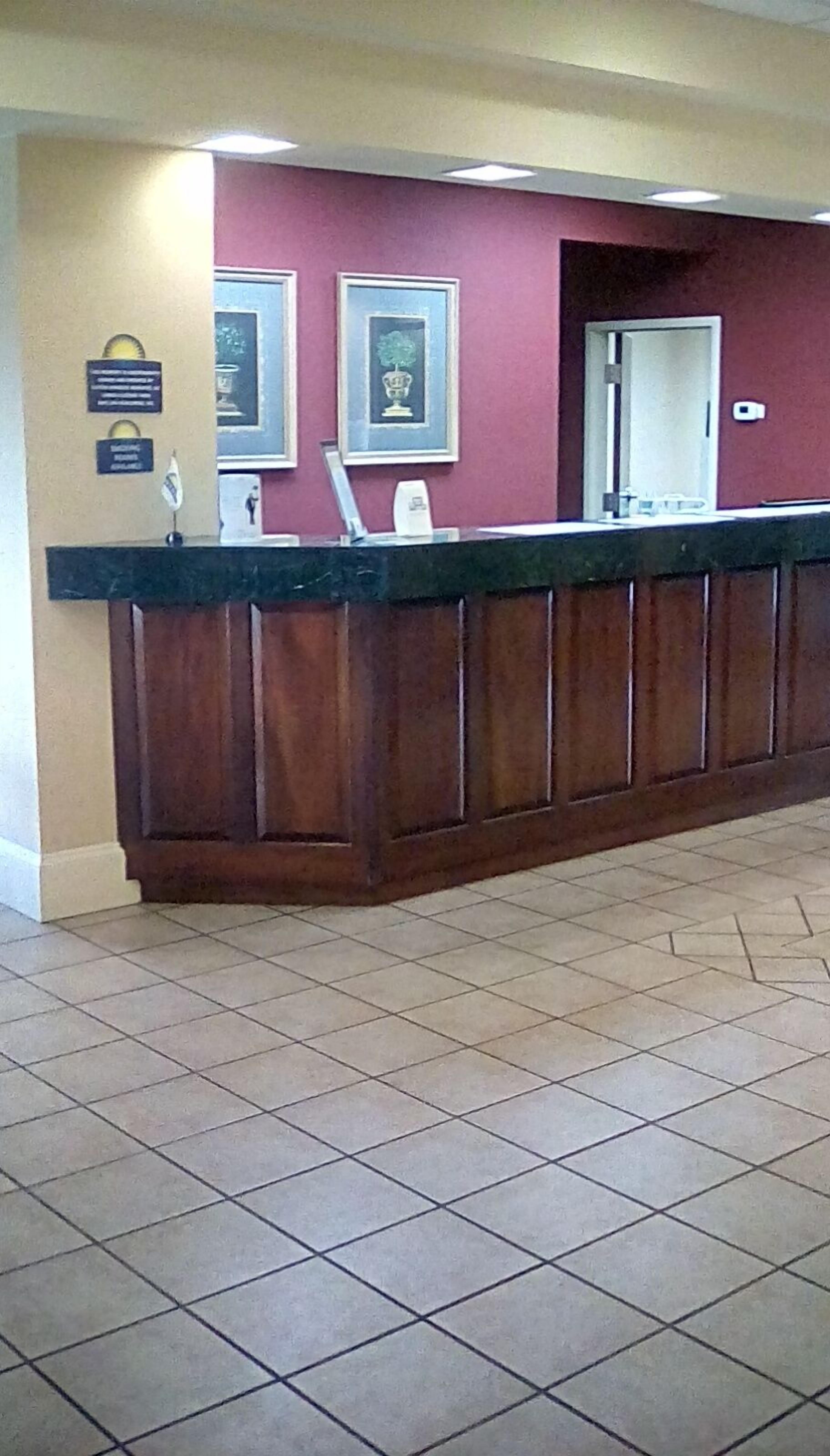 A reception desk with a tiled floor, framed pictures on the wall, and a door to the right.