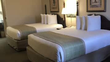 A hotel room with two beds, a bedside table with a lamp, and a framed picture on the wall.