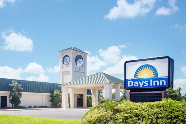 A Days Inn hotel with a clock tower, a covered entrance, and a clear blue sky.