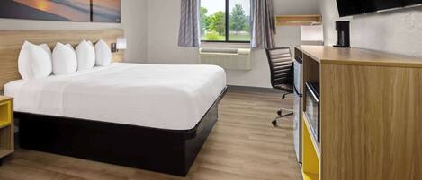 A hotel room with a large bed, a desk, a chair, a flat-screen TV, and a window with curtains.