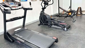 A gym with treadmills, a stationary bike, and dumbbells.