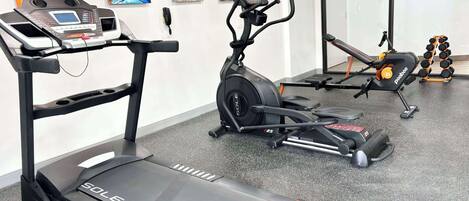 Une salle de sport équipée de tapis de course, d’un vélo d’appartement et d’haltères.
