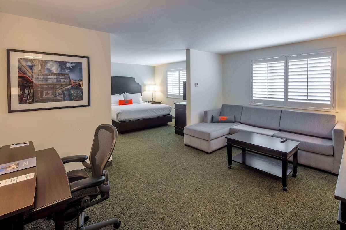 Una habitación de hotel con una cama, un sofá, un escritorio y una silla.