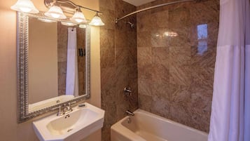 A bathroom with a sink, mirror, and bathtub.