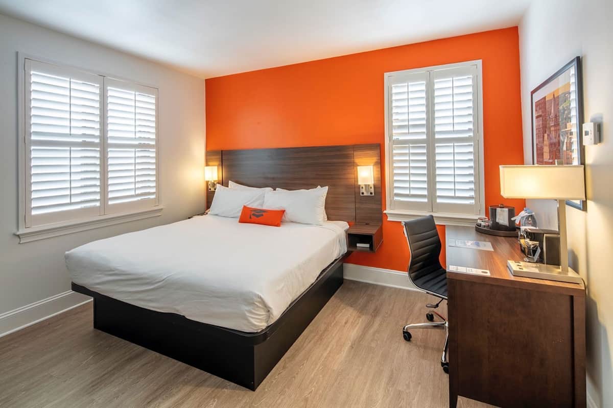 Una habitación de hotel con cama, escritorio, silla y dos mesitas de noche.