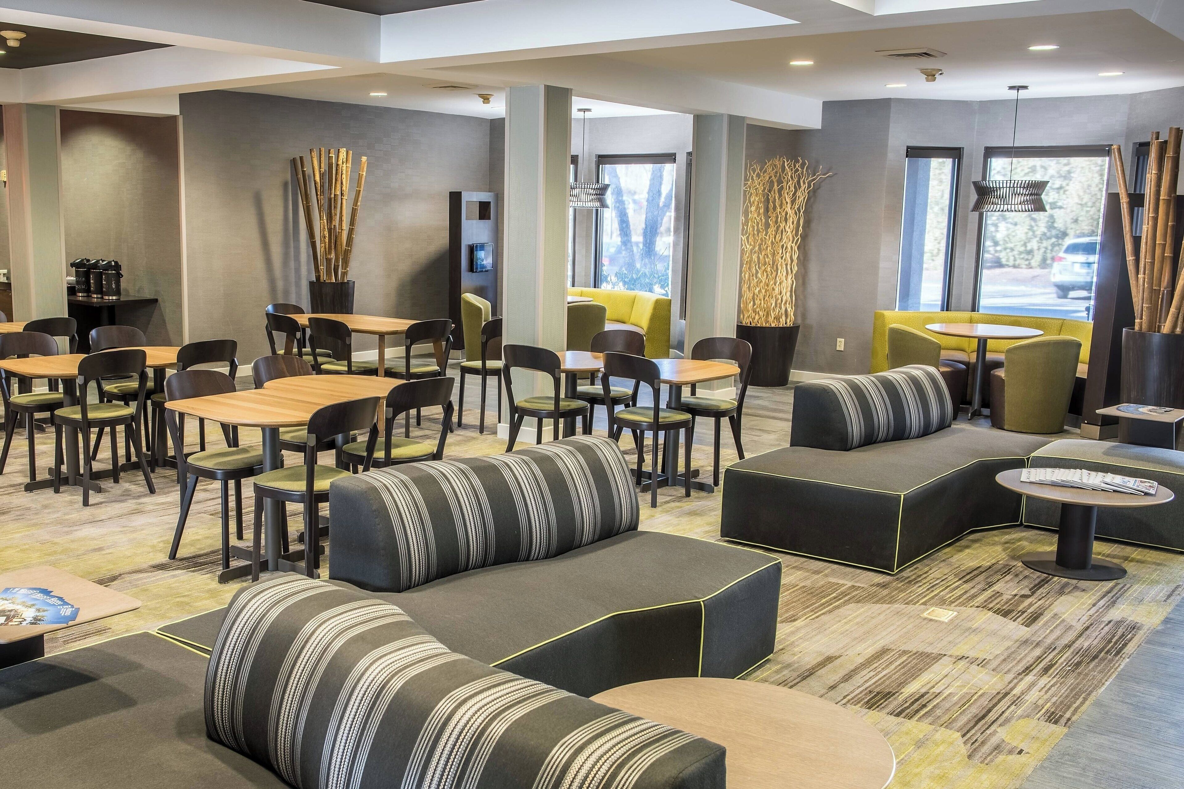 A modern lounge area with seating arrangements, tables, and a coffee machine.