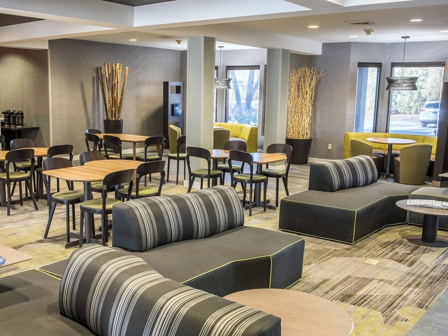 Un espace de détente moderne, aménagé avec des sièges, des tables et une machine à café.