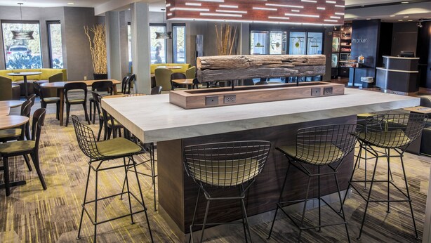Eine moderne Bar mit einer zentralen Theke, Barhocker und einer Lounge mit Tischen und Stühlen.