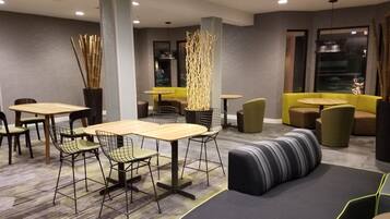 A modern lounge area with multiple seating options including tables, chairs, and sofas.