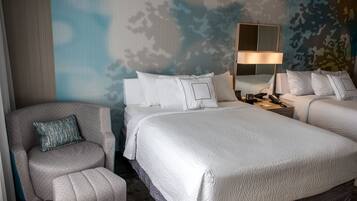 Habitación de hotel con dos camas, una silla, una lámpara y una pared con estampado de camuflaje.