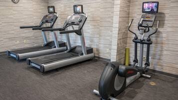 Een sportschool met loopbanden, crosstrainers en een hometrainer.