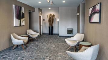 A hotel lobby with a patterned carpet, modern chairs, and artwork on the walls.