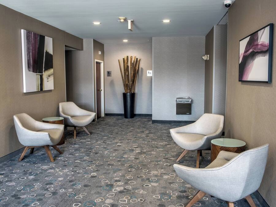 A hotel lobby with a patterned carpet, modern chairs, and artwork on the walls.