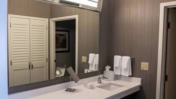 A modern bathroom with a large mirror, a sink, and a toilet.