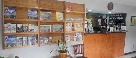 A reception area with a wooden desk, a potted plant, and a caution sign on the floor.