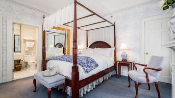 Una cama con dosel, una mesita de noche con lámpara, una silla y un banco.