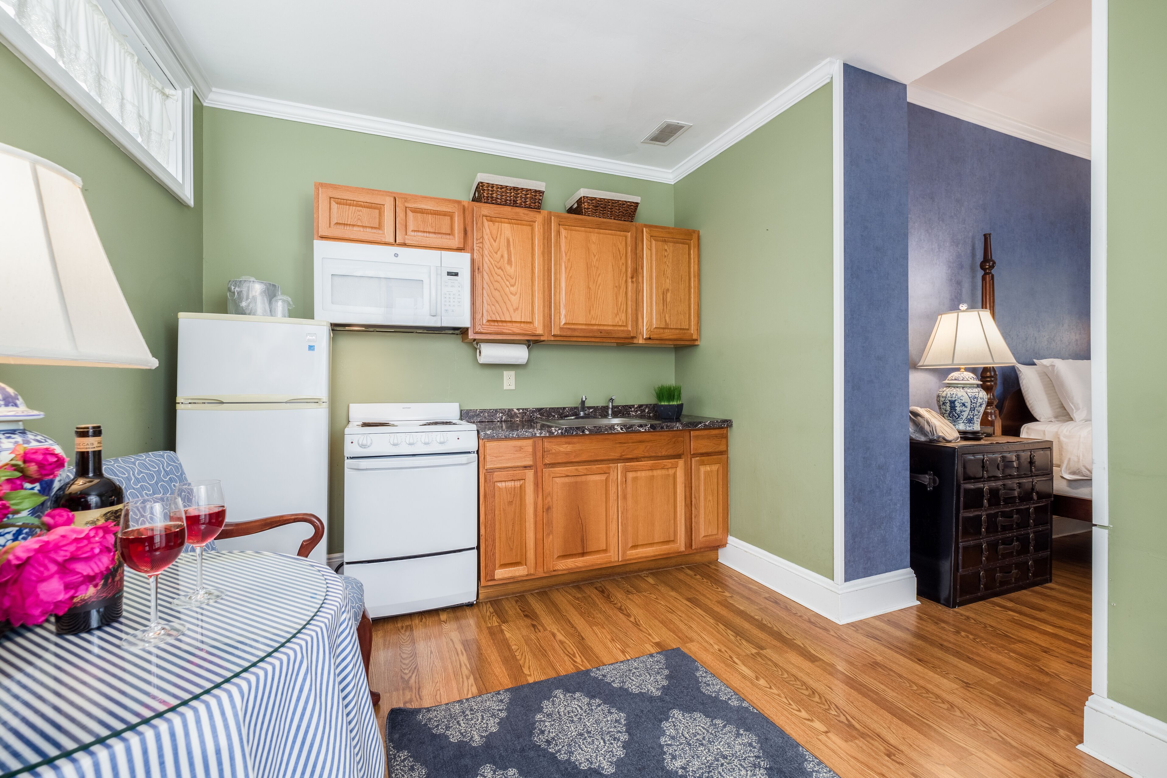 A compact kitchen with wooden cabinets, a white refrigerator, and a microwave.