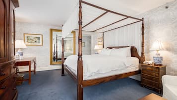 A four-poster bed with a wooden frame, a bedside table with a lamp, and a dresser with drawers.