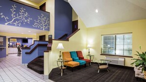 A modern living room with a staircase, a dining area, and a view of the outside. - Days Inn by Wyndham Blue Springs (Blue Springs)