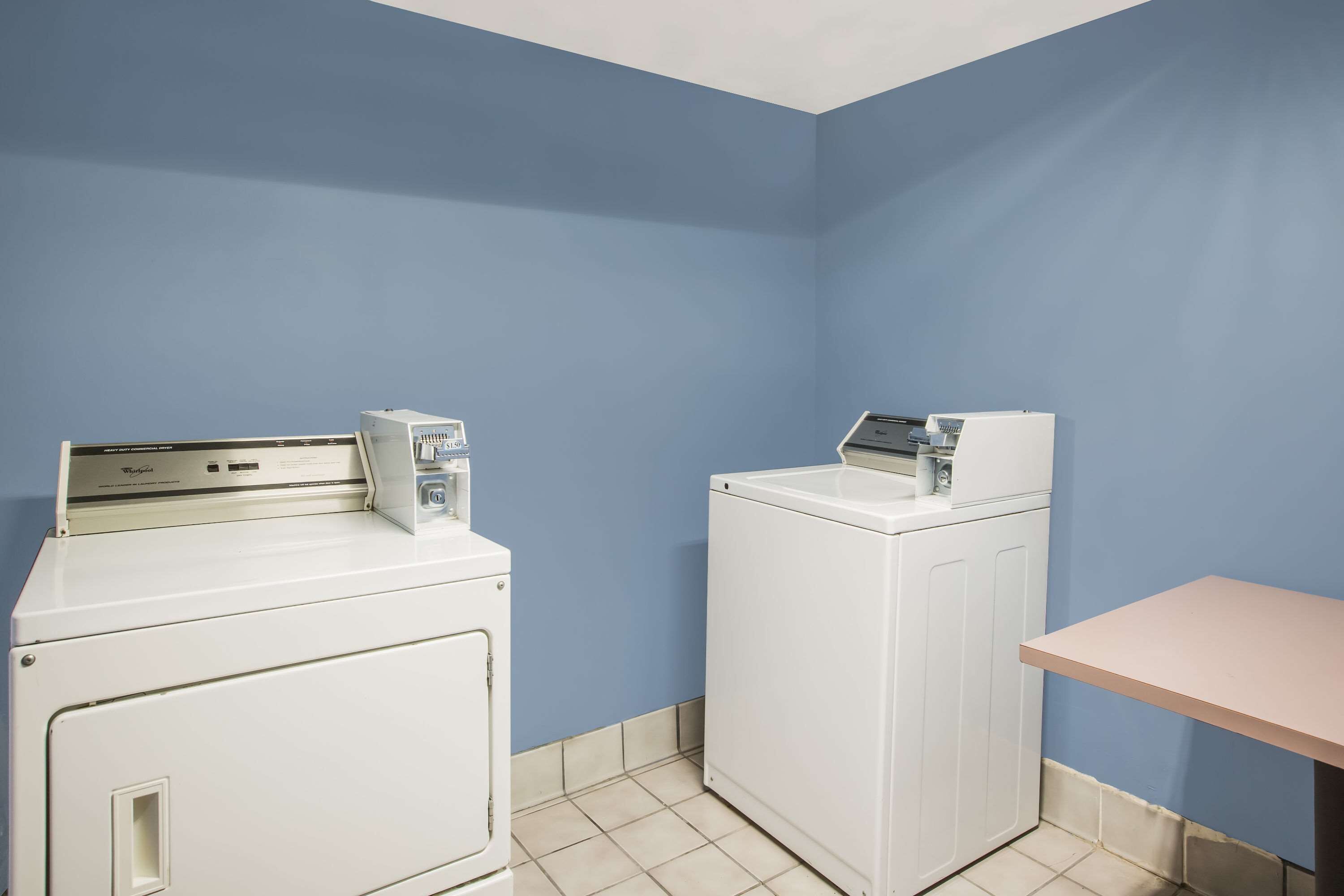 A laundry room with two white washing machines and a small table.