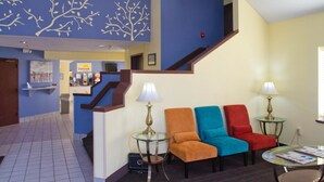 A hotel lobby with a staircase, a reception desk, and three chairs with lamps. - Days Inn by Wyndham Blue Springs (Blue Springs)