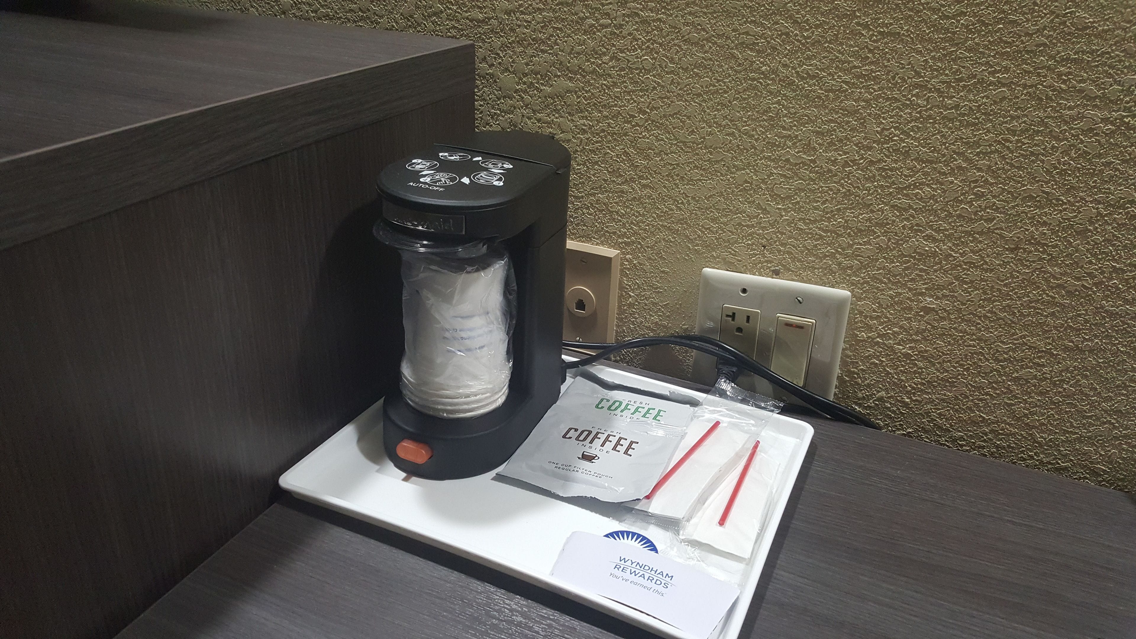 A coffee maker with a coffee pod and a card on a table.