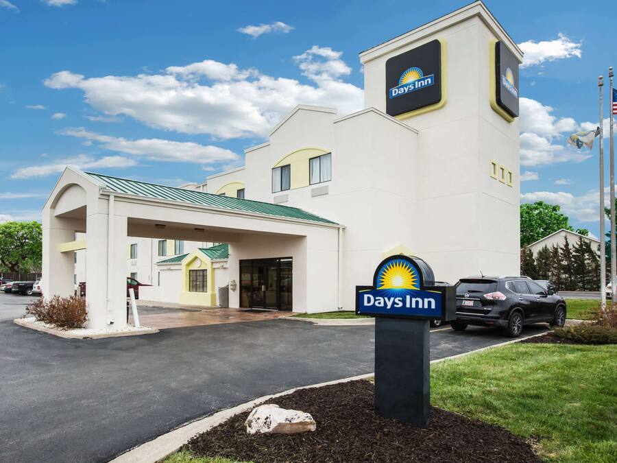 A Days Inn hotel with a modern design, featuring a prominent sign, a covered entrance, and a parking area.