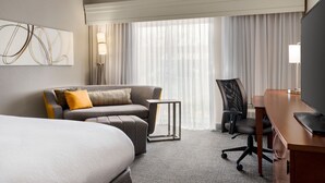 Une chambre d’hôtel avec un lit, un canapé, un bureau et une télévision.